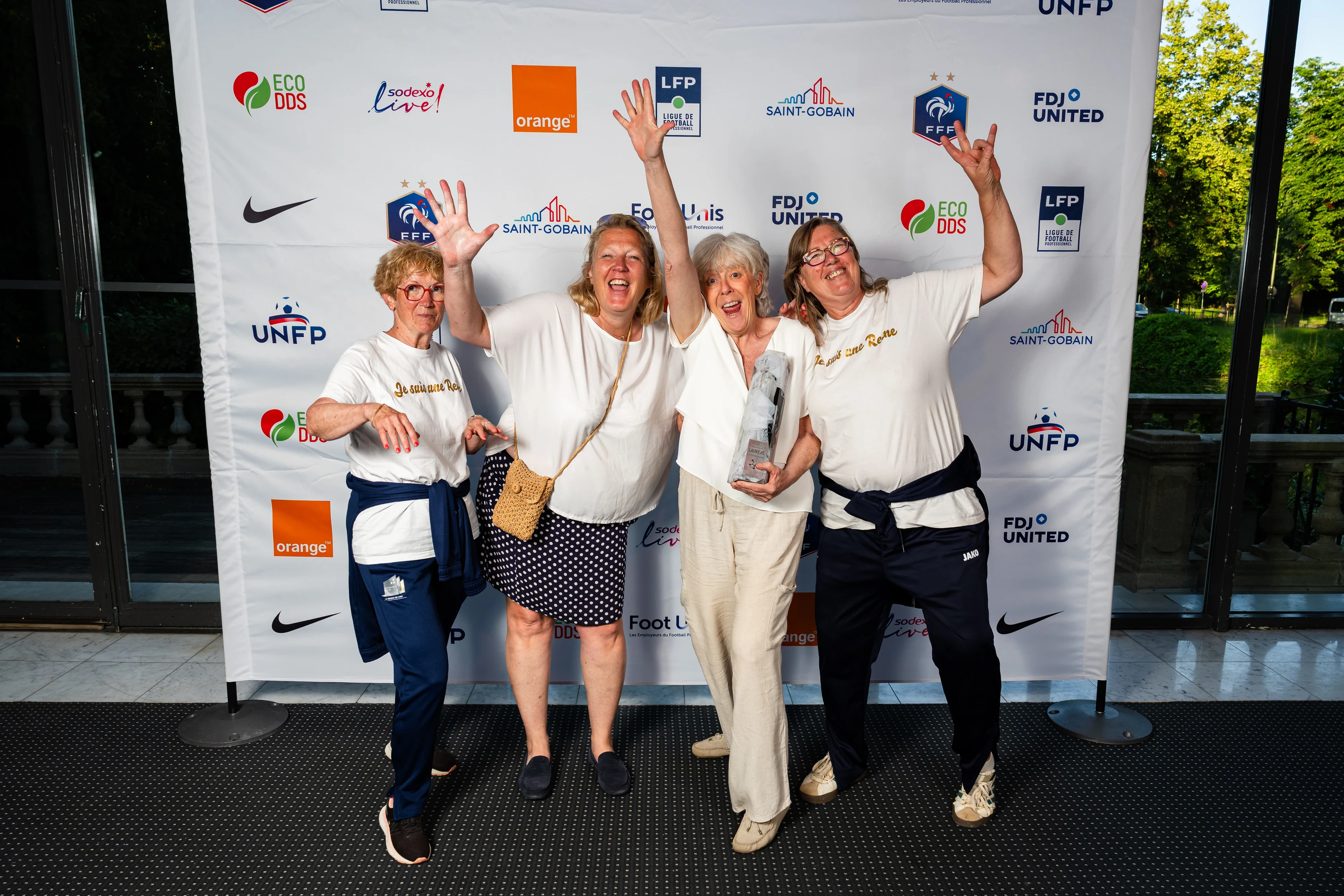Des lauréates lèvent les bras devant le photocall, trophée en main