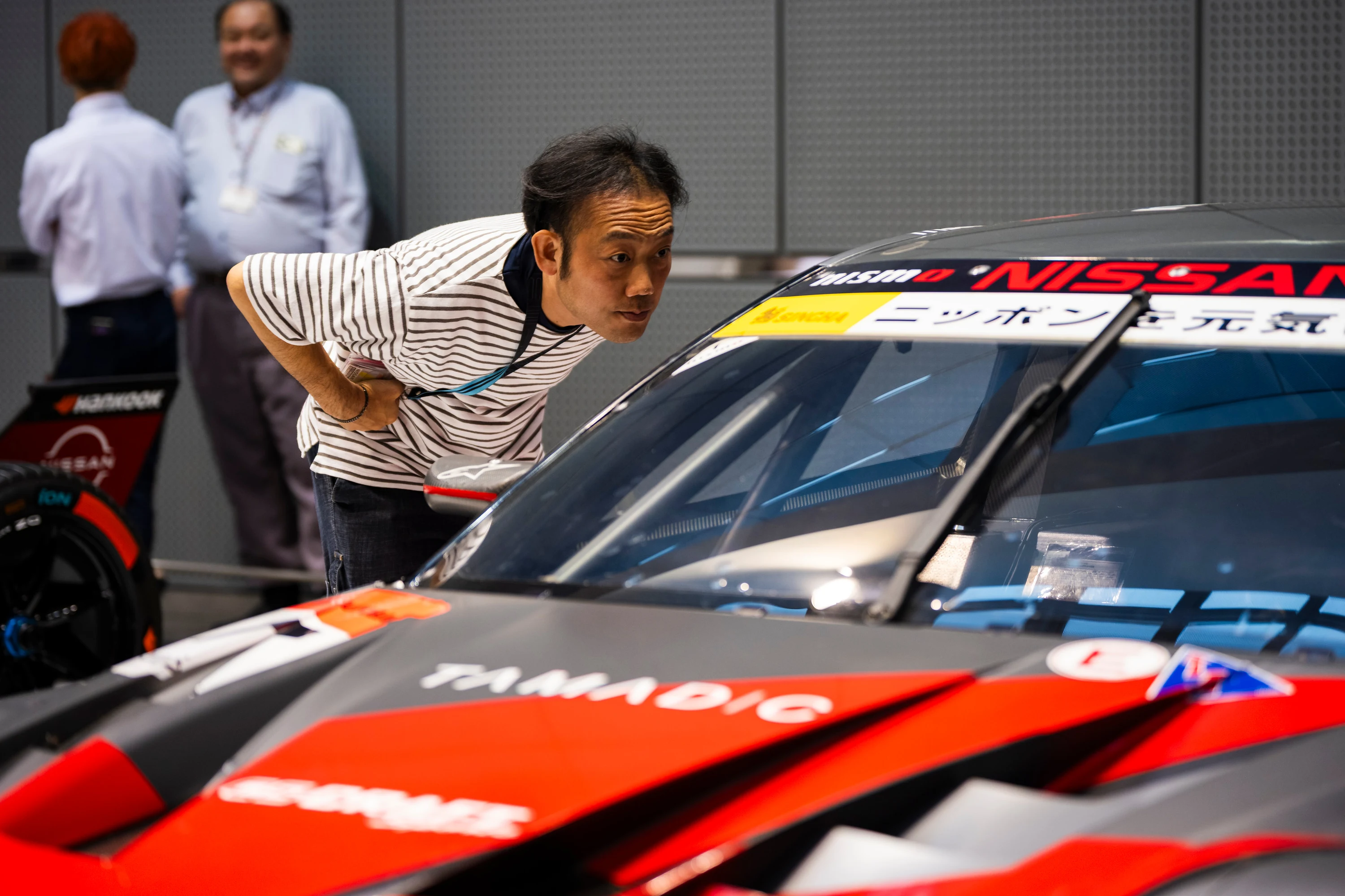 Un visiteur observe de près la Nissan Z GT500 du championnat Super GT