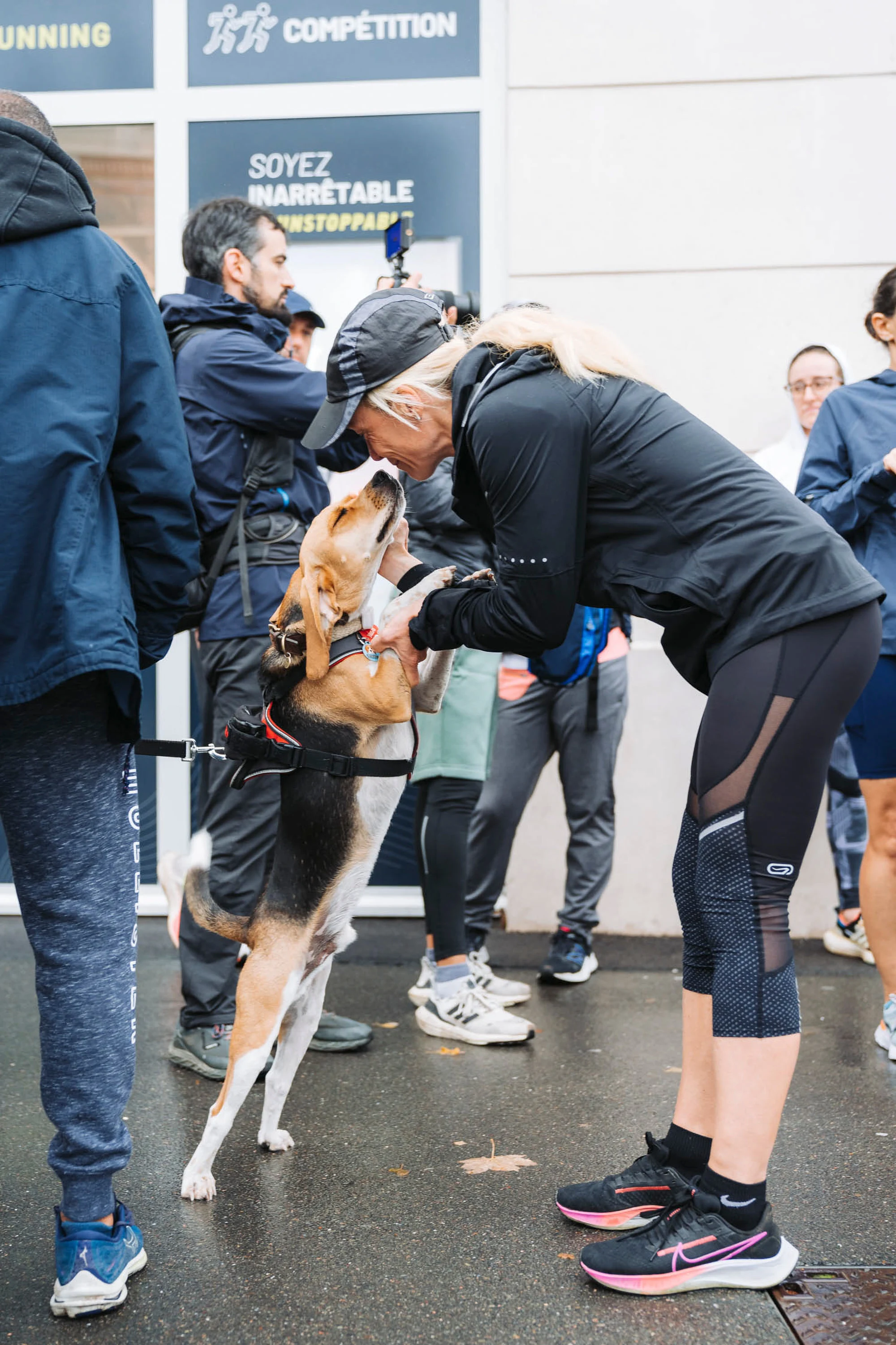 Une participante salue un chien avant le départ, devant une banderole Garmin