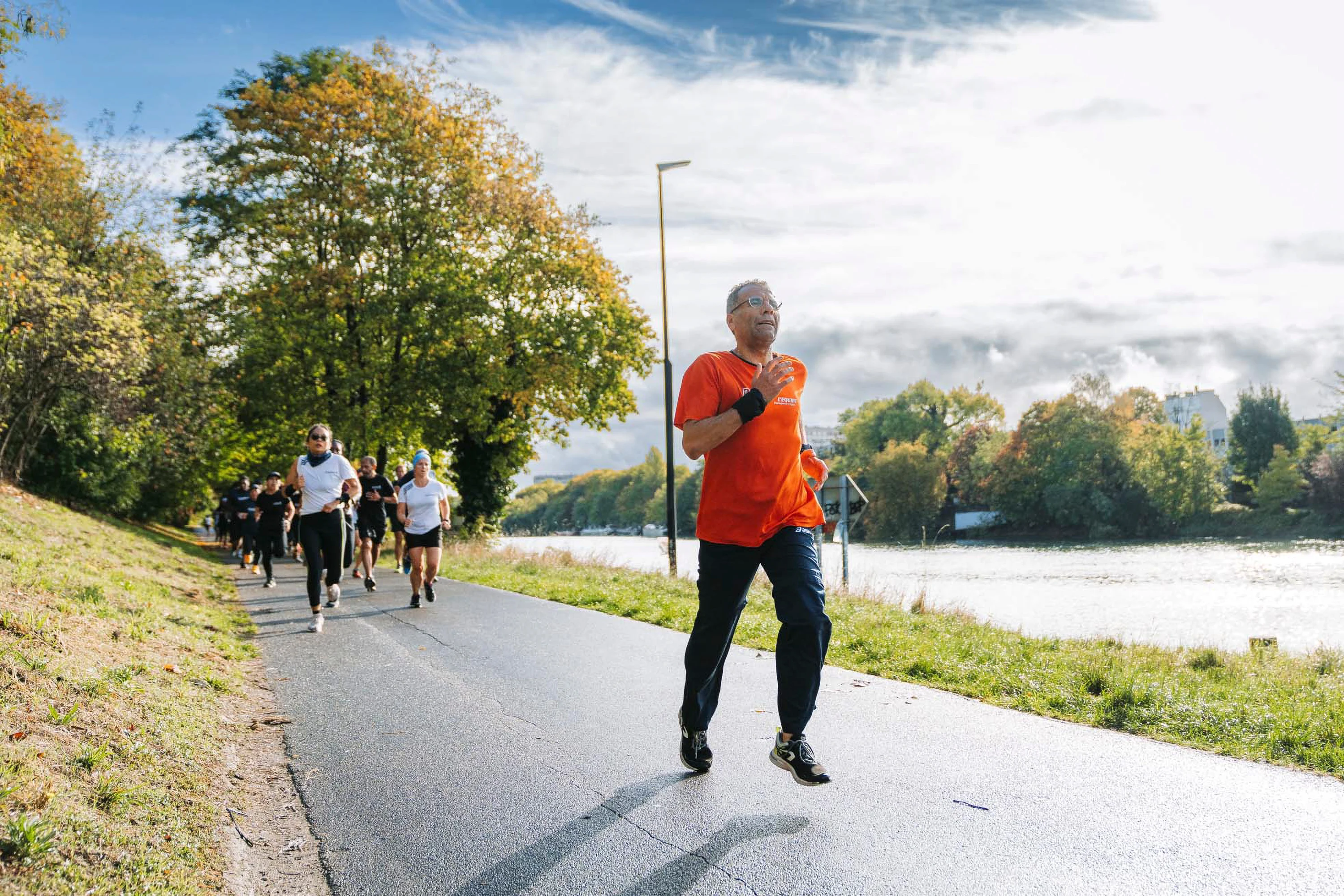Un coureur en t-shirt orange remonte le chemin le long du plan d'eau