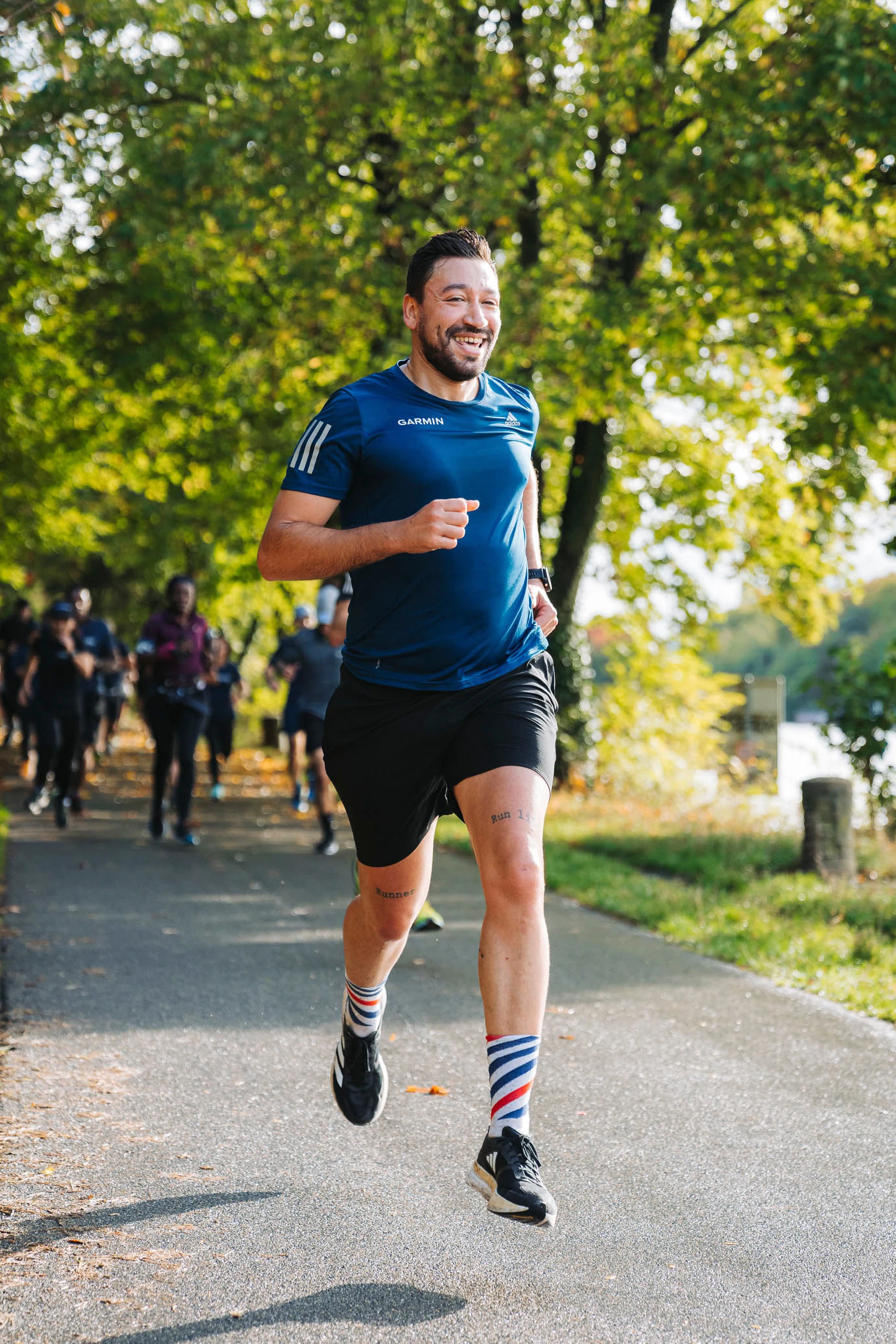 Un coureur souriant sur le chemin bordé d'arbres