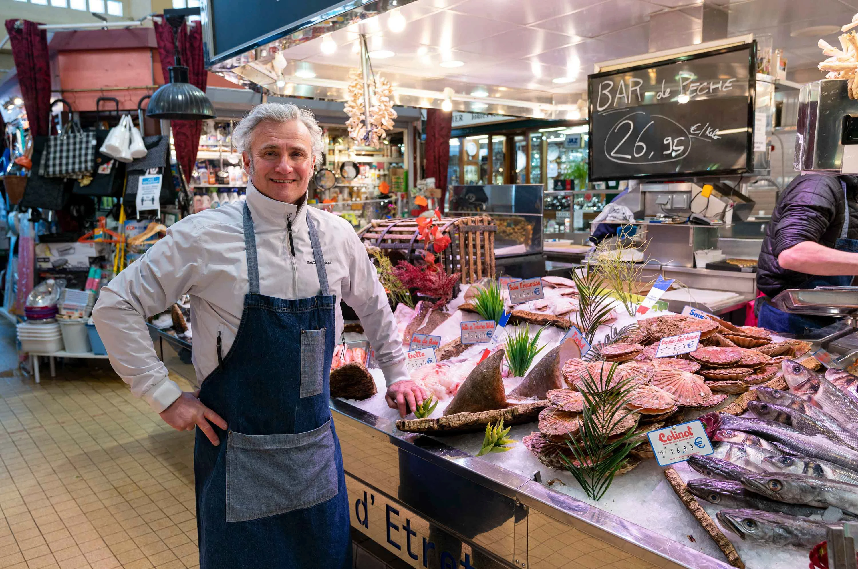 Un poissonnier derrière son étal, sous la halle