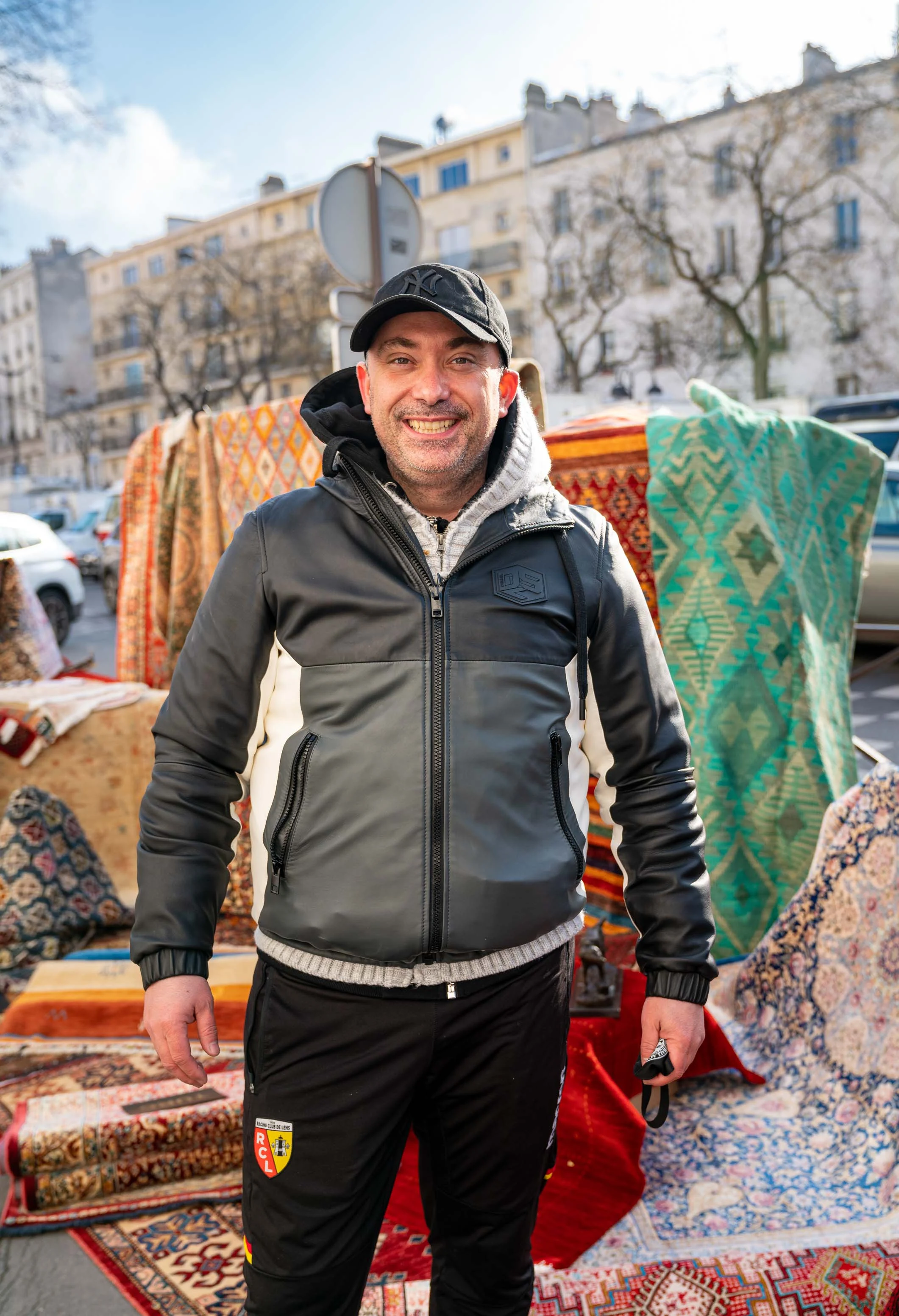 Un marchand de tapis devant sa marchandise, sur le trottoir