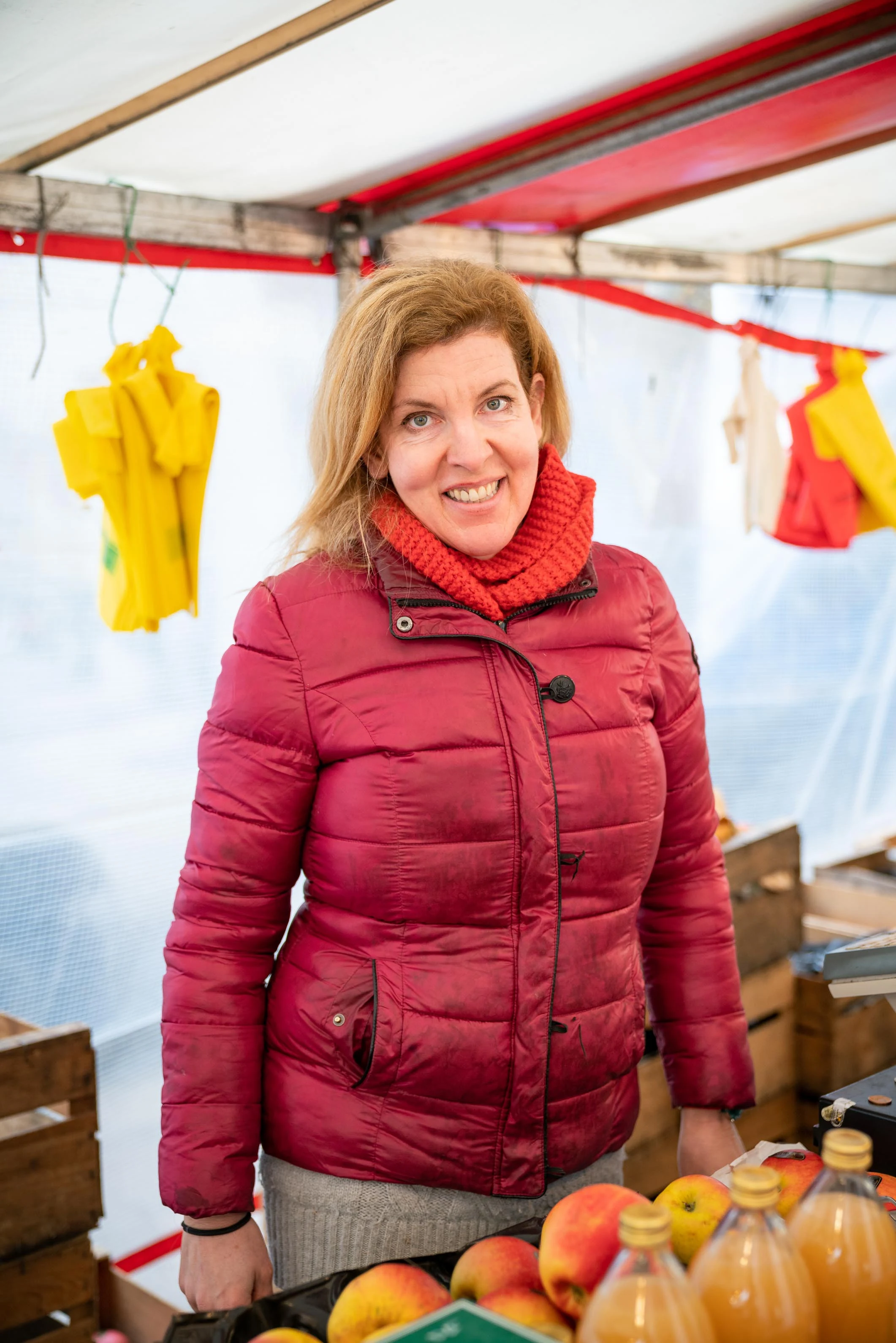 Une commerçante en doudoune rouge devant ses fruits