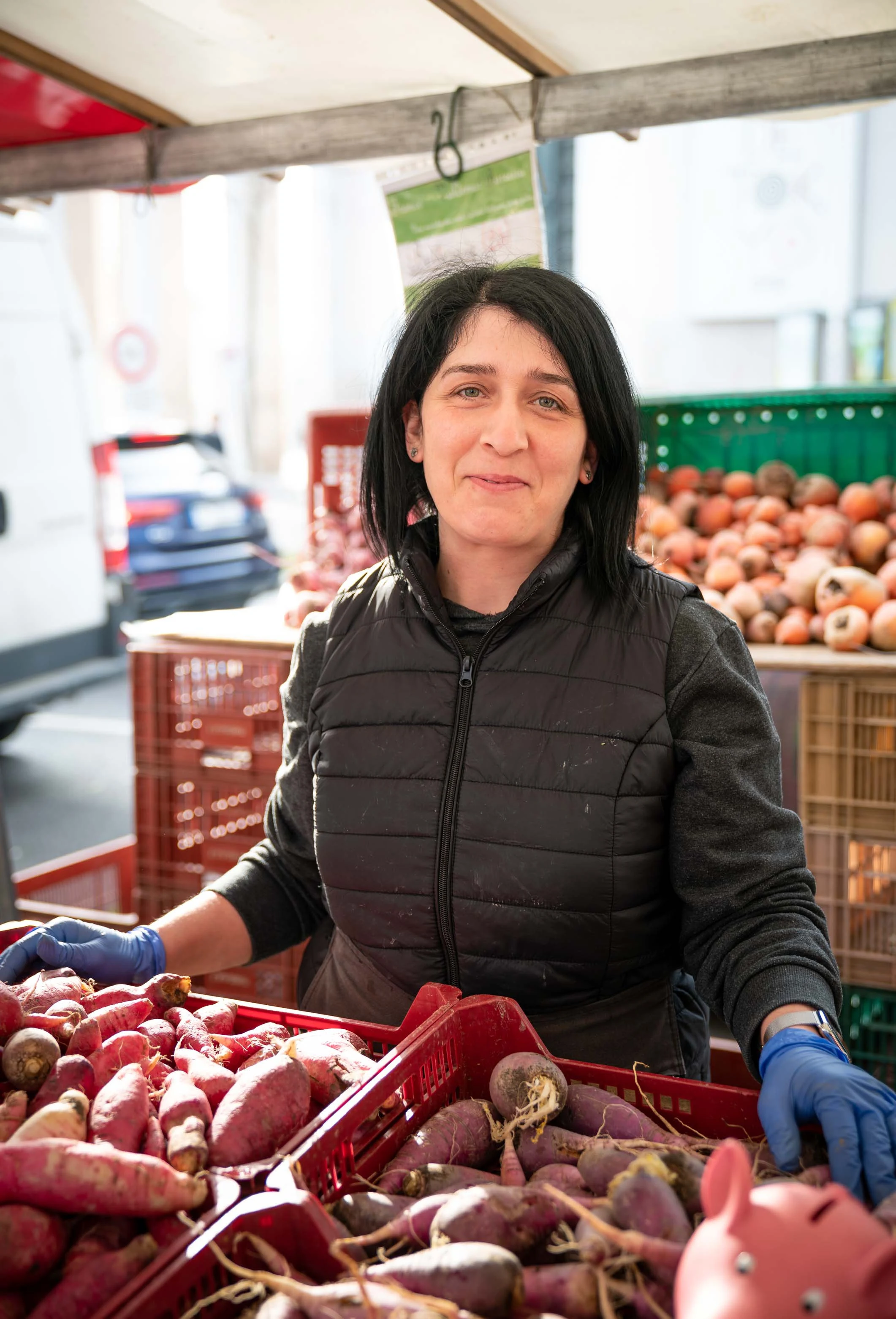 Une commerçante range des légumes racines dans sa caisse