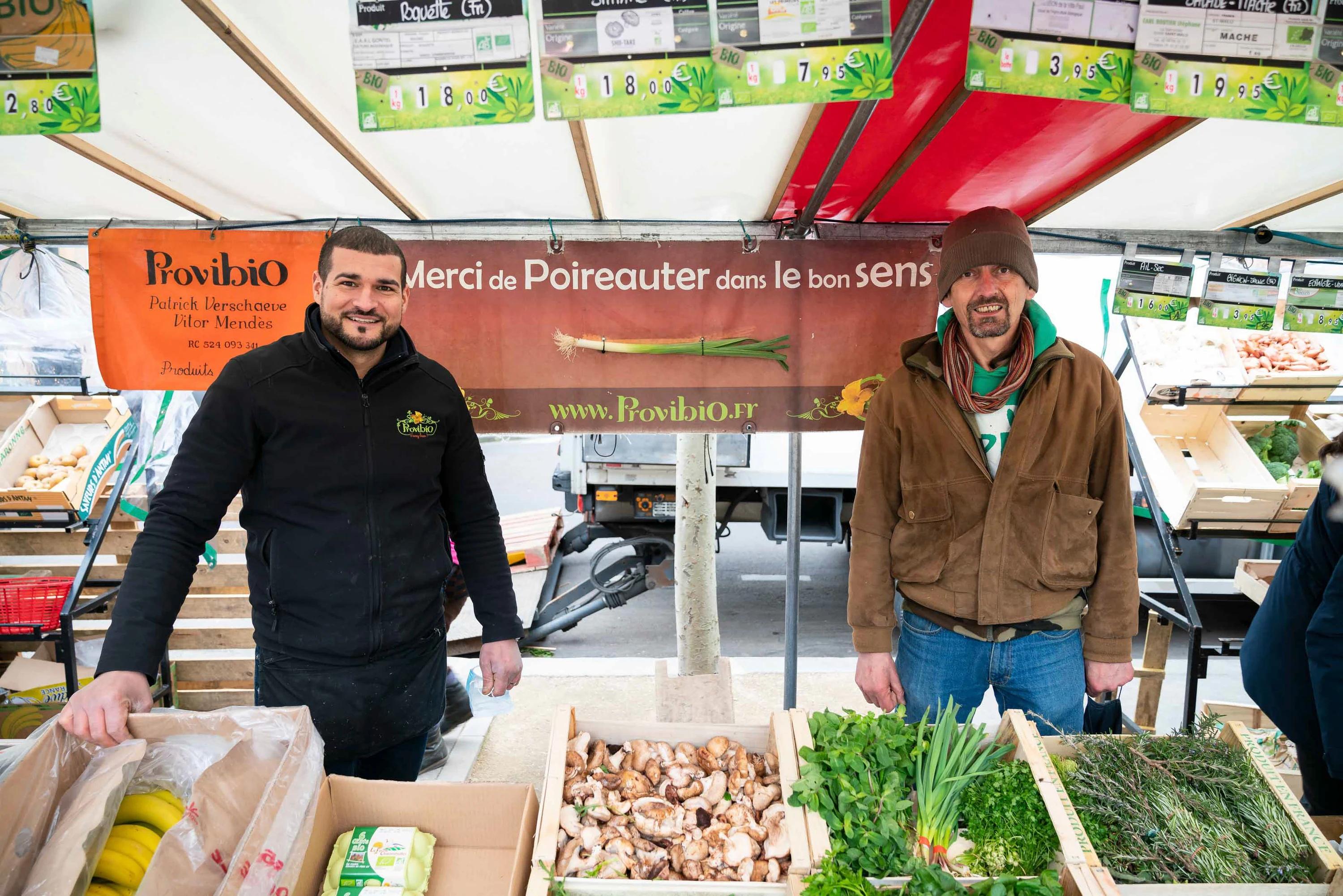 Deux maraîchers derrière leurs cageots de légumes