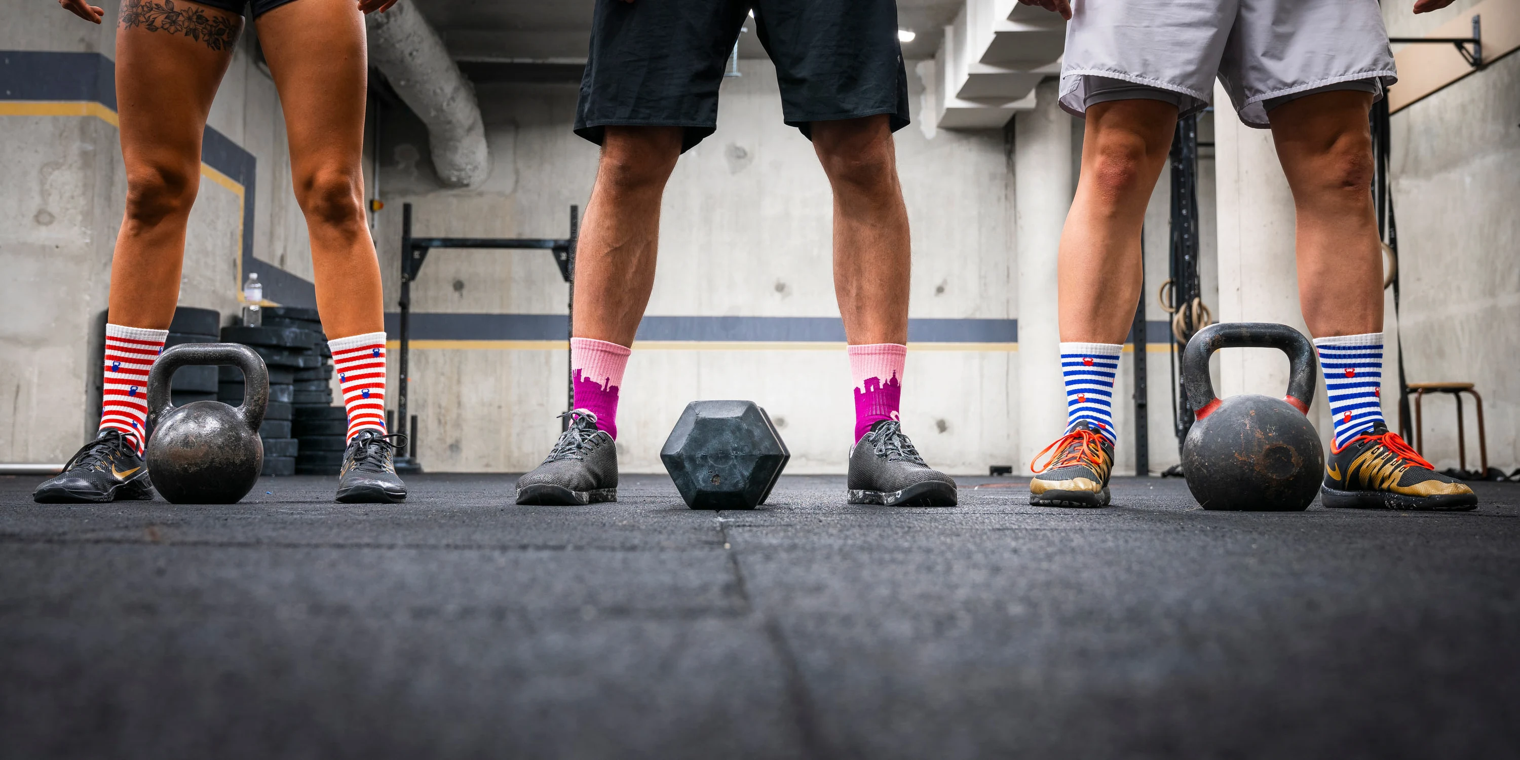 Quatre paires de jambes en chaussettes, les kettlebells posées au sol