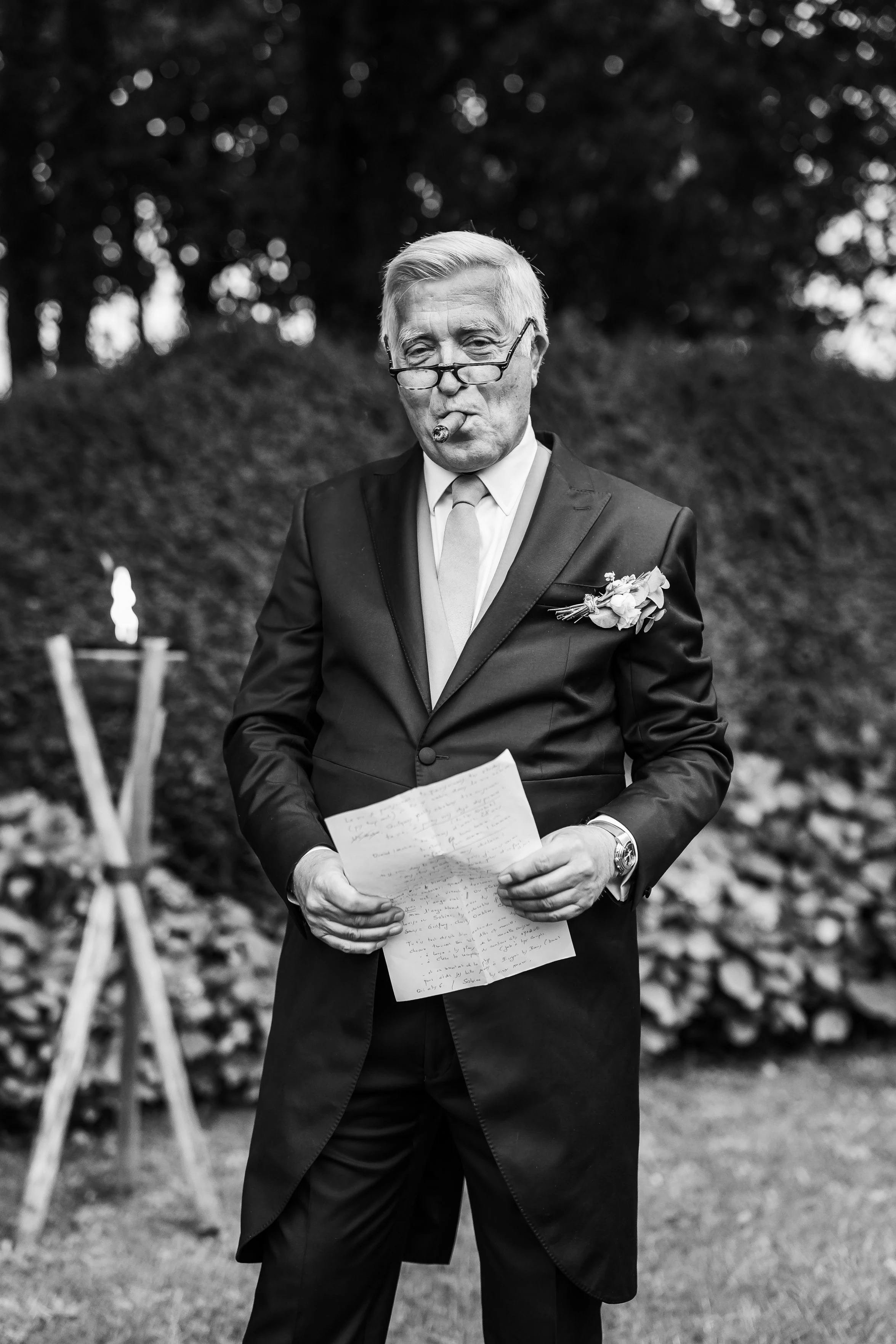 Noir et blanc : un invité lit son discours devant un brasero, à la nuit tombée