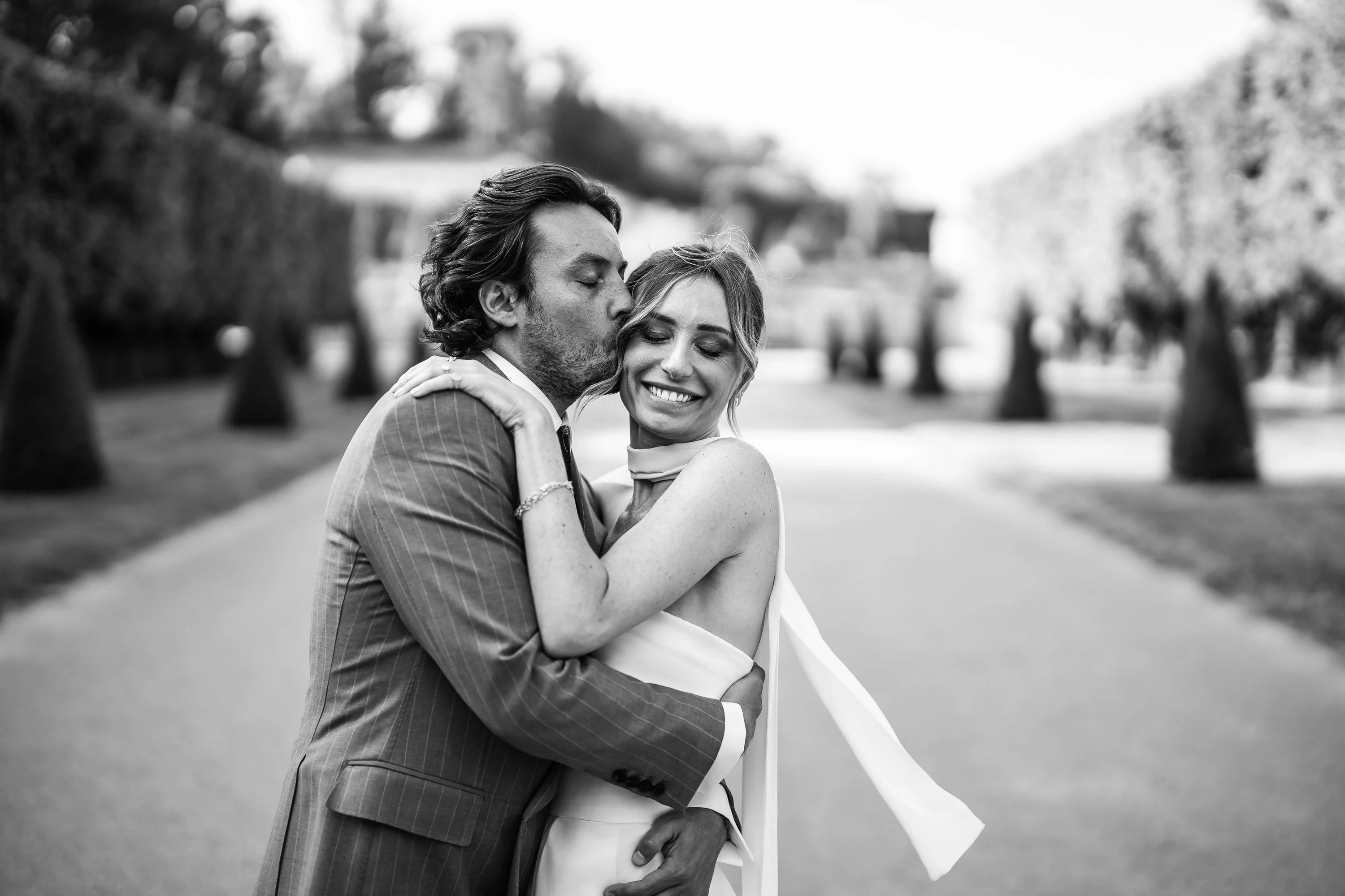 Noir et blanc : un baiser dans une longue allée d'arbres taillés