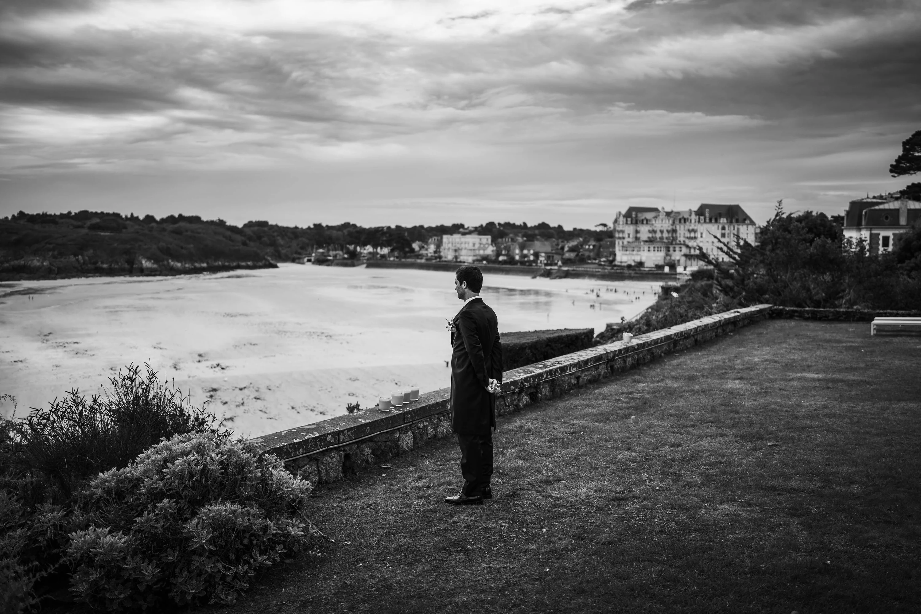 Noir et blanc : un marié seul face à la baie avant la cérémonie
