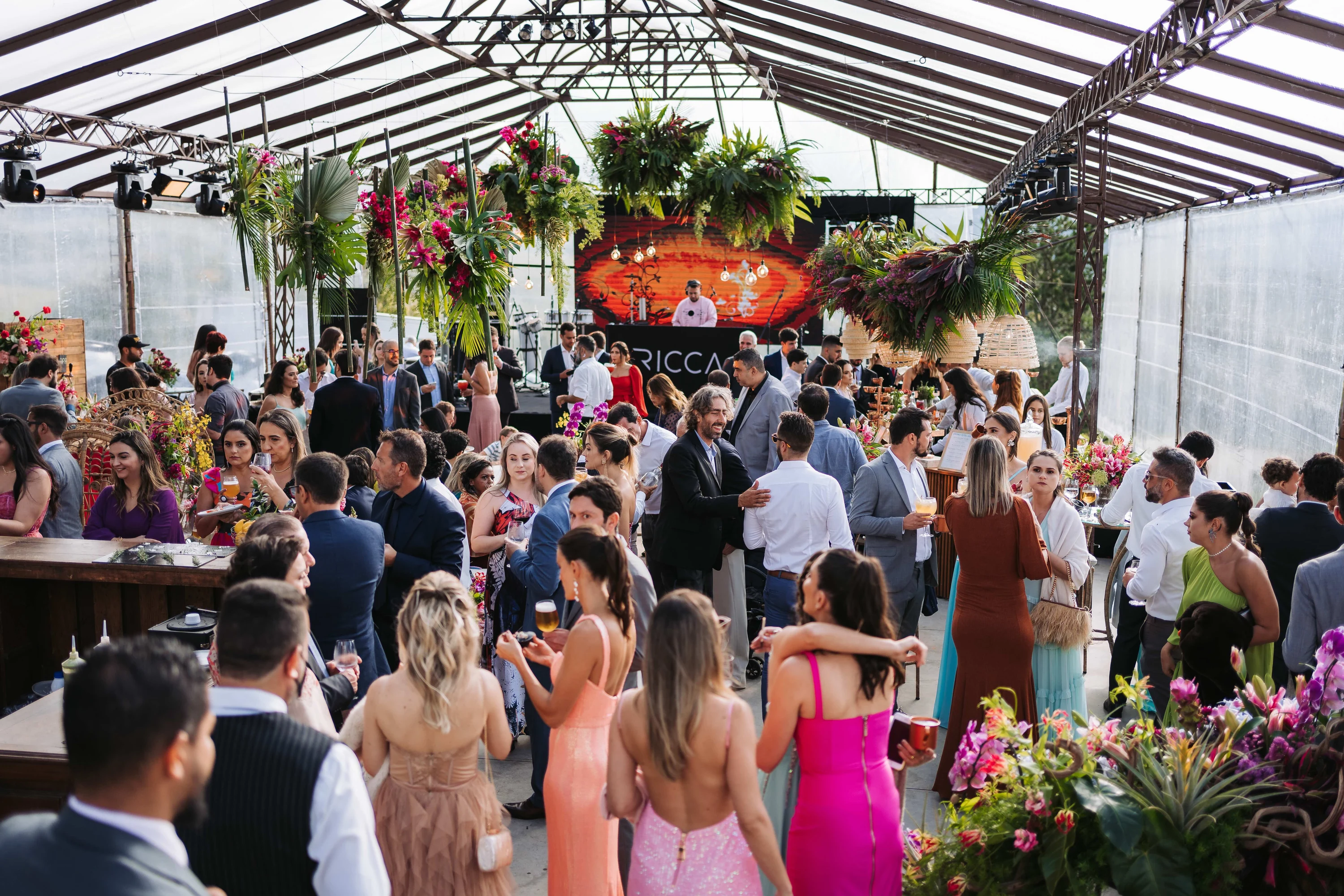 Cocktail sous une verrière fleurie, les invités debout avant le dîner