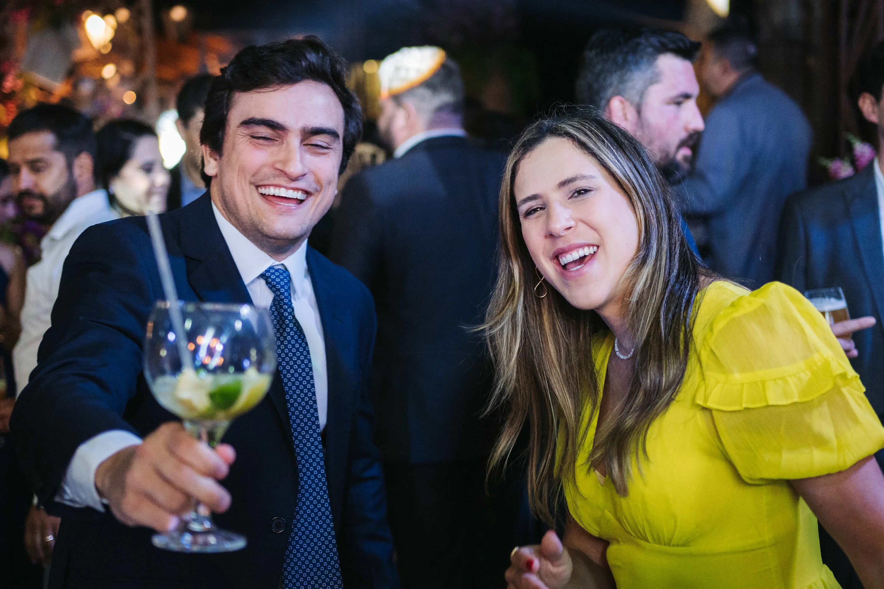 Un invité lève son verre au milieu de la fête, la soirée bat son plein