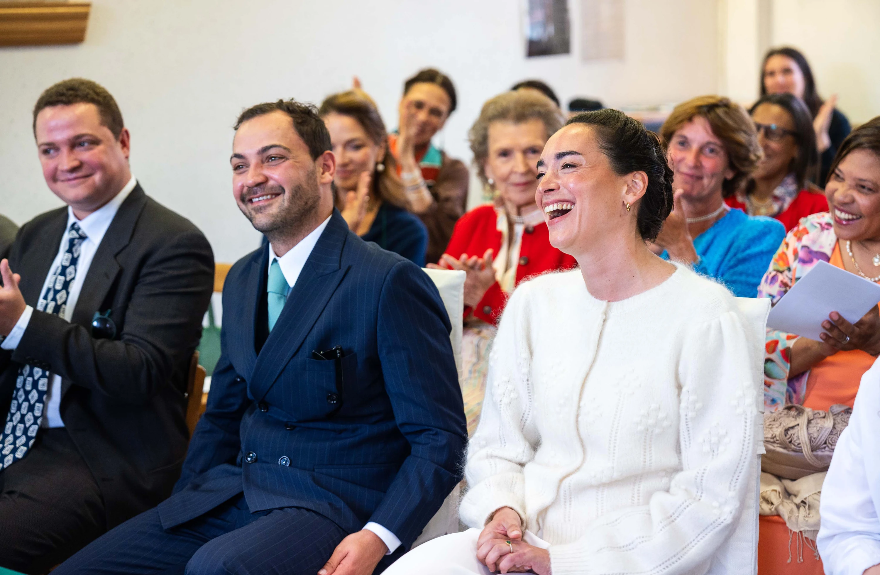 Les mariés éclatent de rire pendant la cérémonie, les invités derrière eux