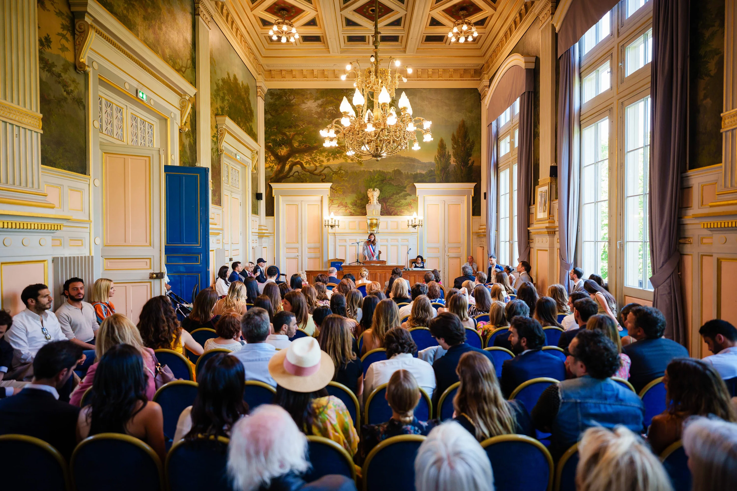 Cérémonie civile dans une salle des mariages au plafond doré, la salle pleine