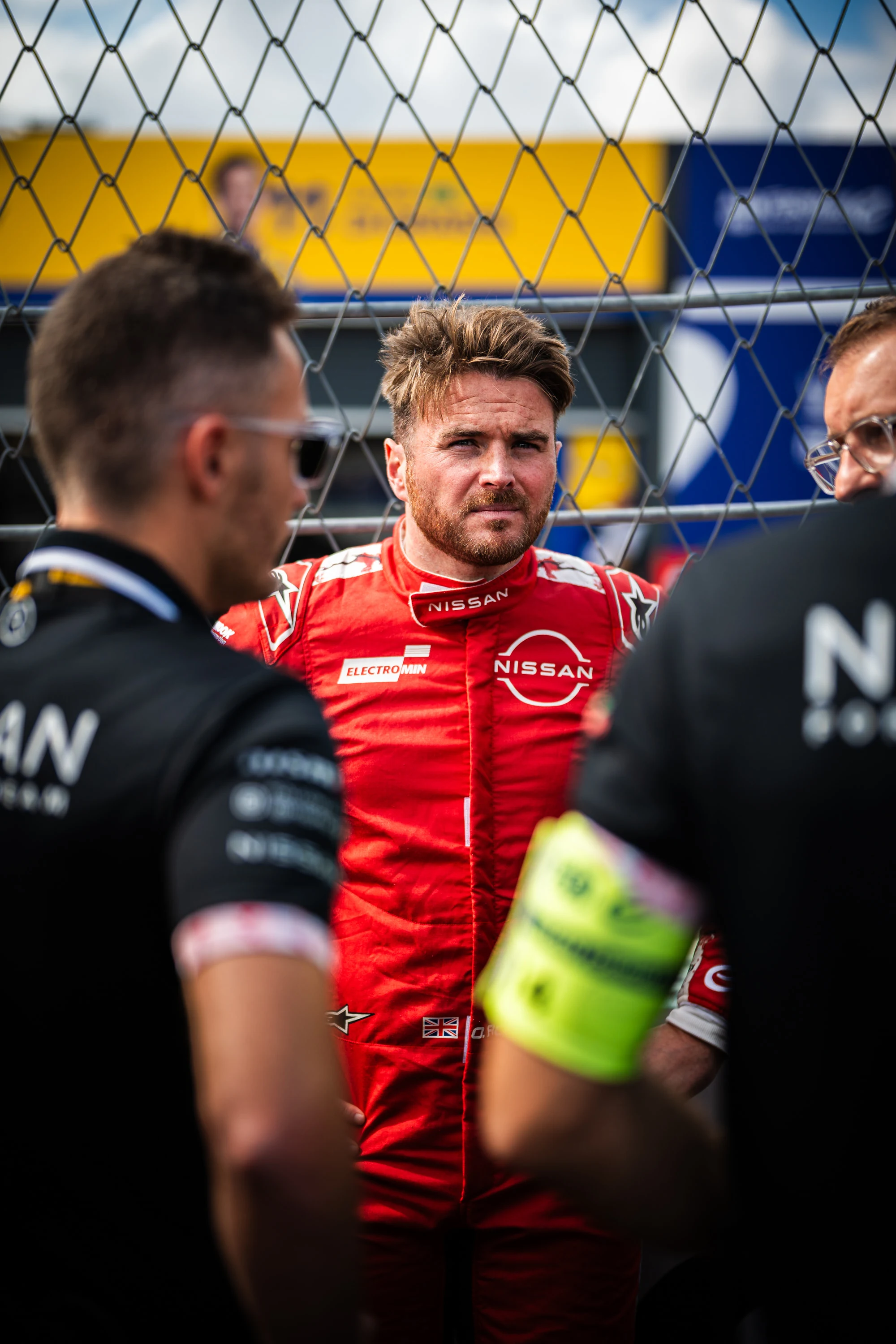 Oliver Rowland concentré sur la grille de départ, vu à travers les grillages du circuit de Tempelhof, E-Prix de Berlin 2025