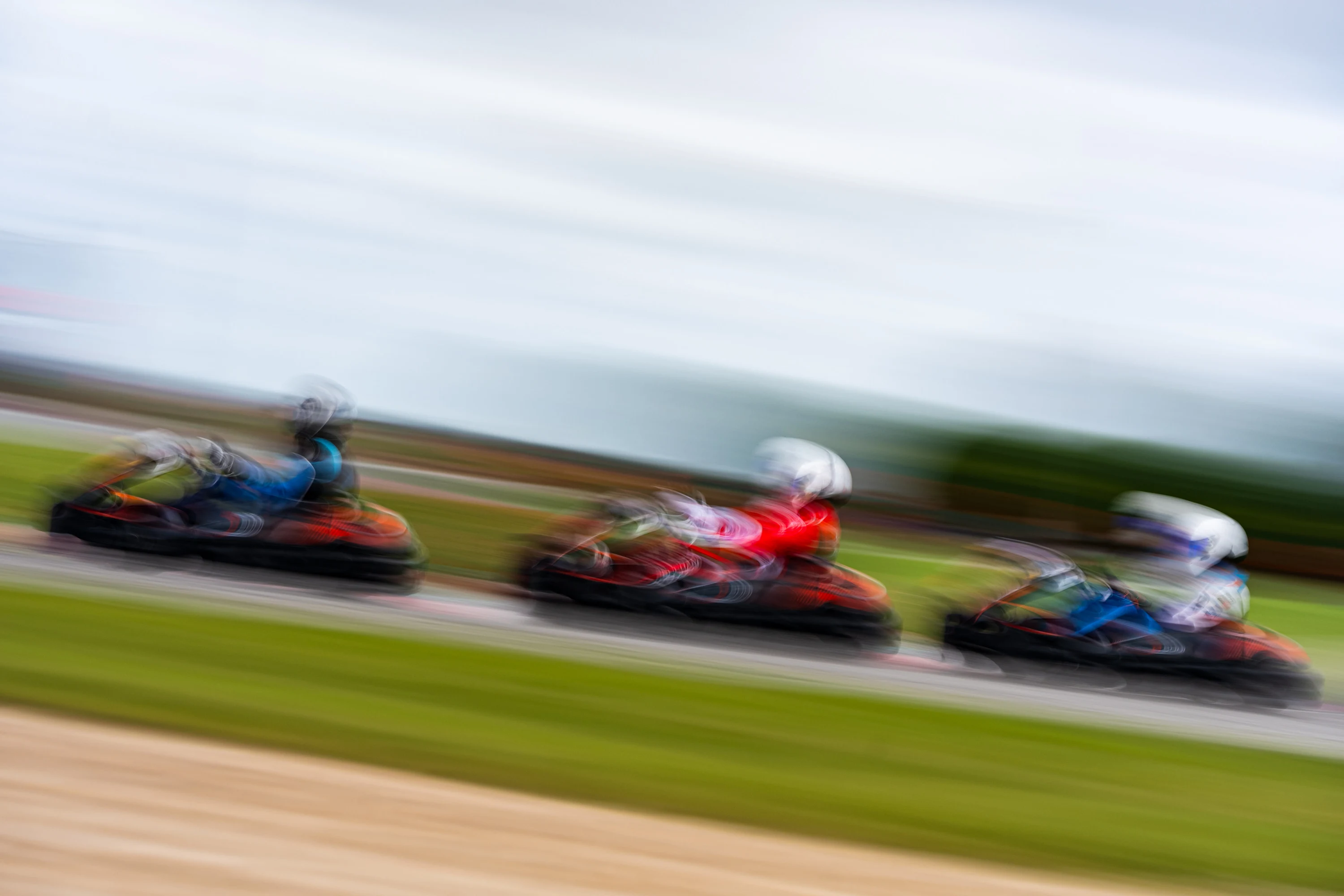Trois karts serrés en pleine attaque, filé au ras de la piste