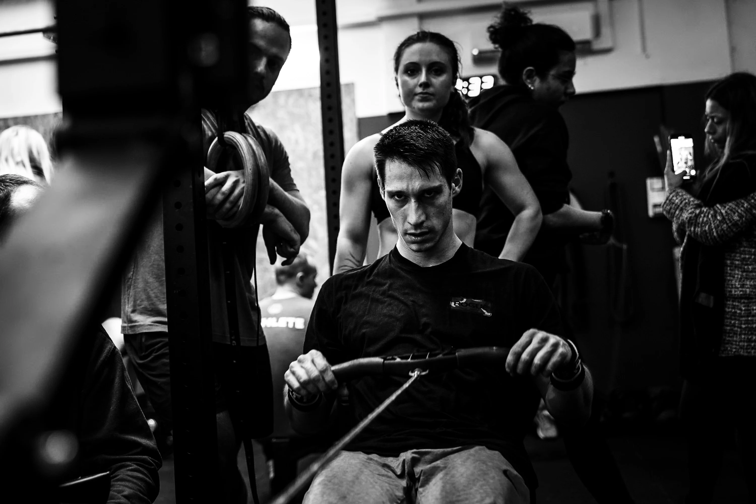 Noir et blanc : un athlète tire sur le rameur, entouré des autres participants