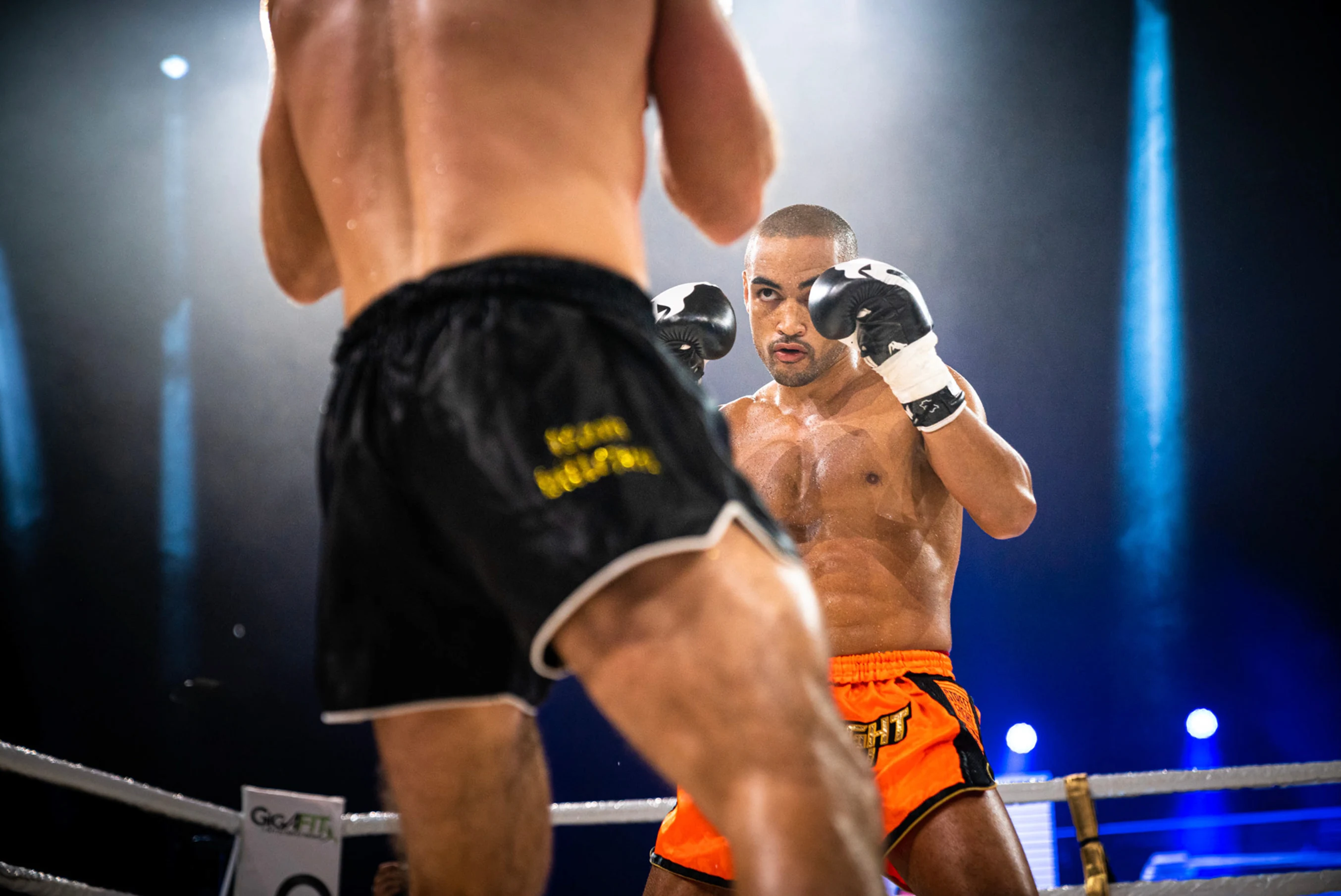 Deux combattants de muay-thaï s'affrontent sur le ring, gants levés