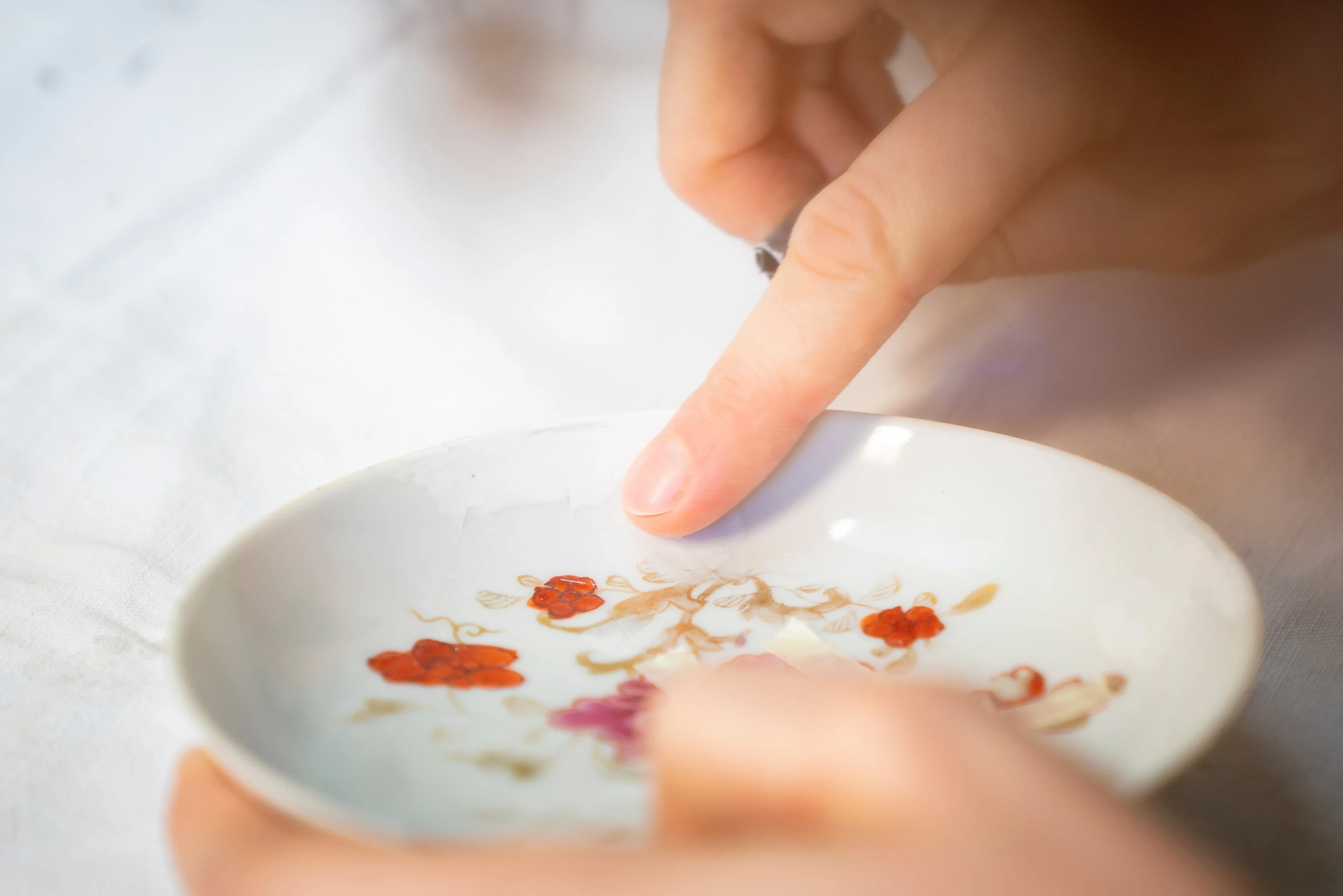 Un doigt prélève de la couleur dans une coupelle de porcelaine