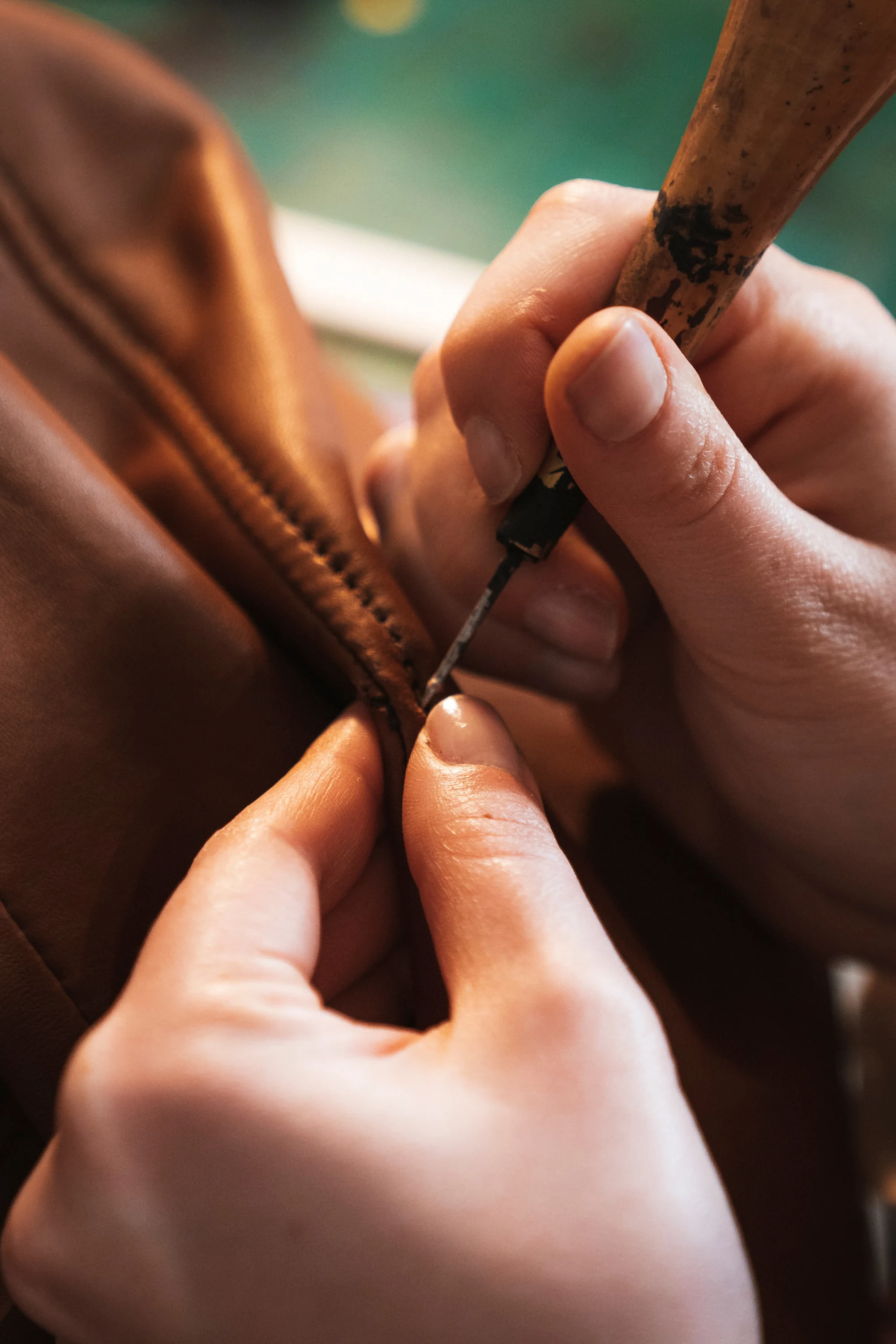 Des mains lissent la tranche d'un cuir à l'outil