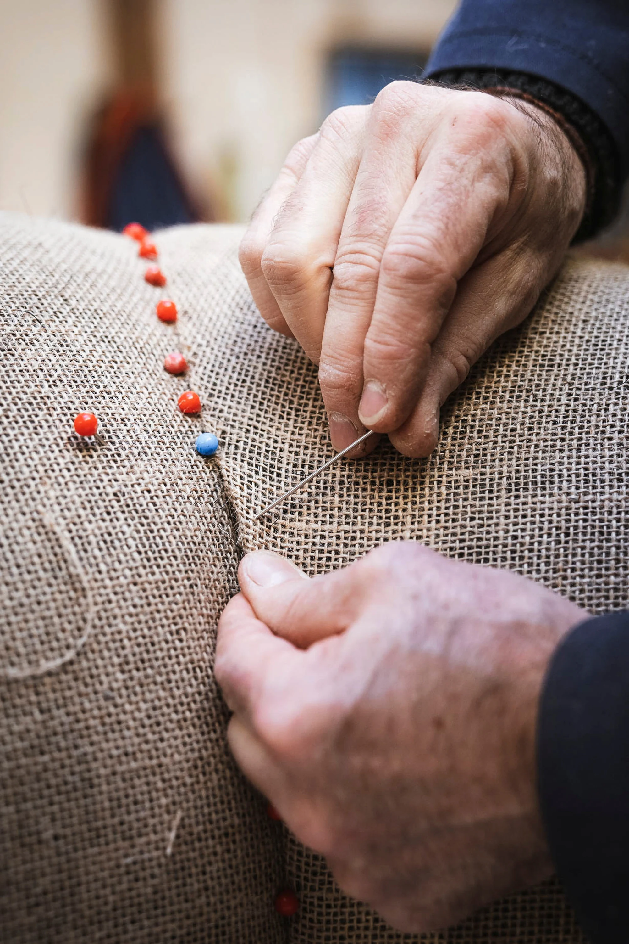 Un tapissier pose des semences sur une toile de jute tendue