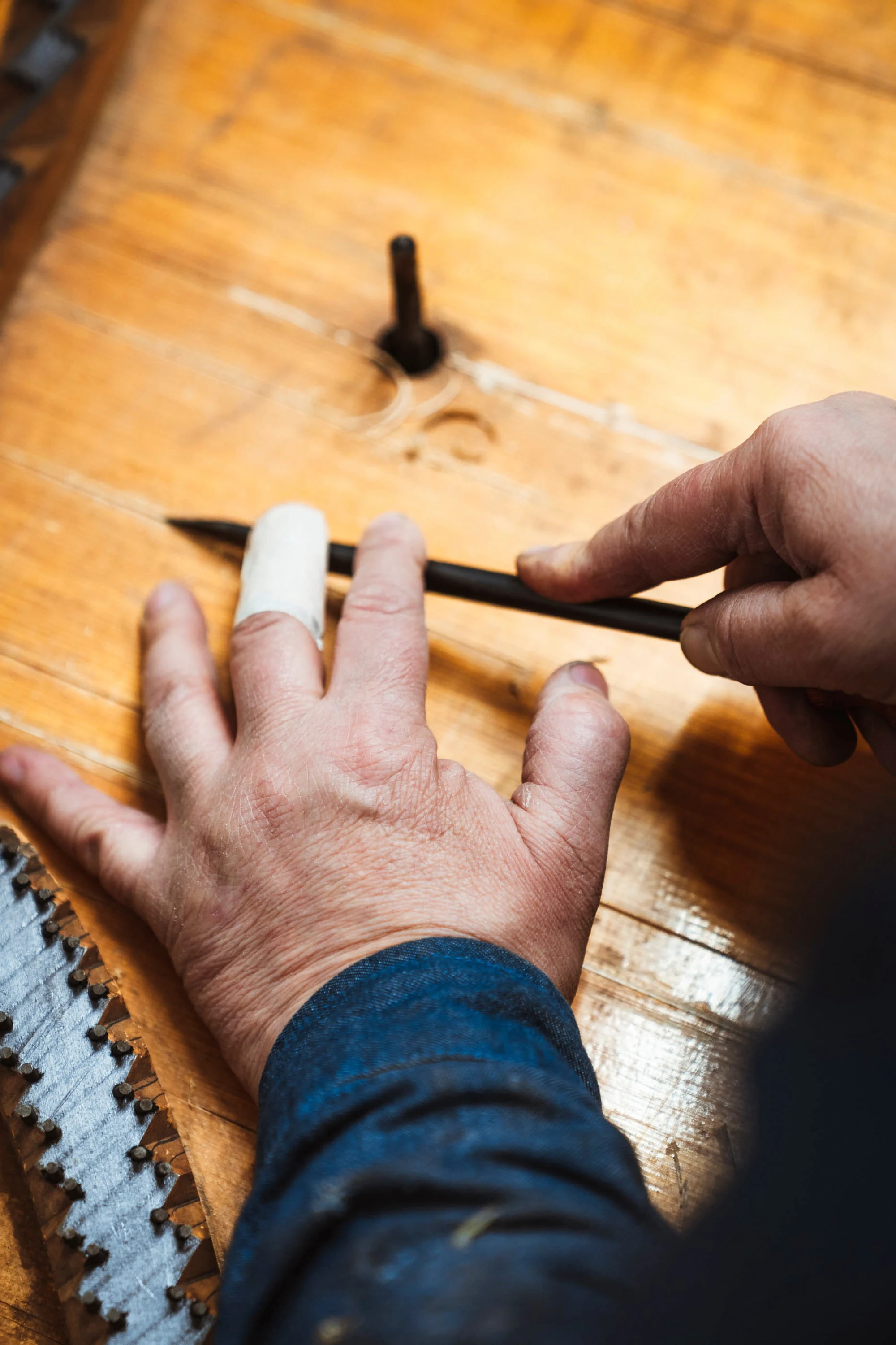 Un artisan trace au crayon sur un plateau de bois
