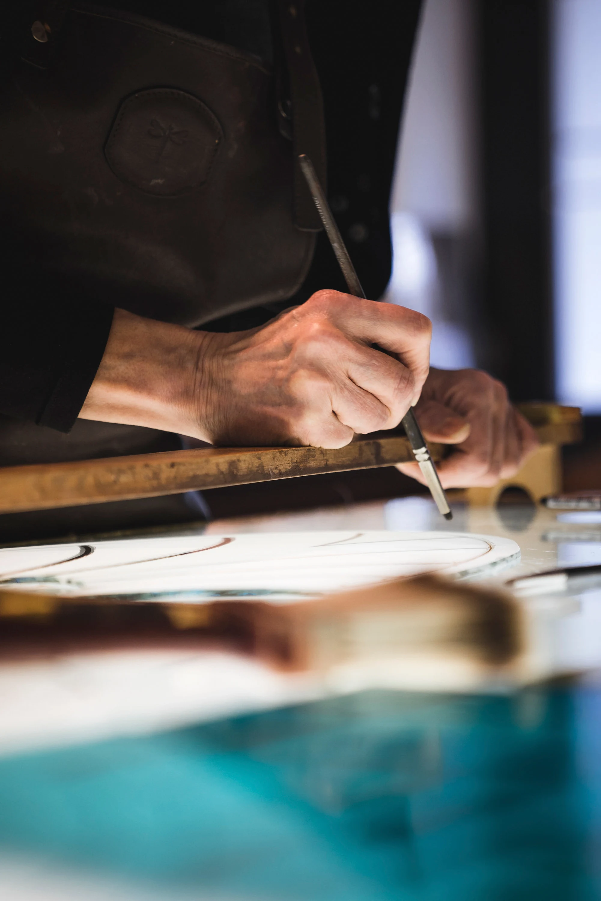 Une main travaille à la pointe sur une pièce en cours de restauration
