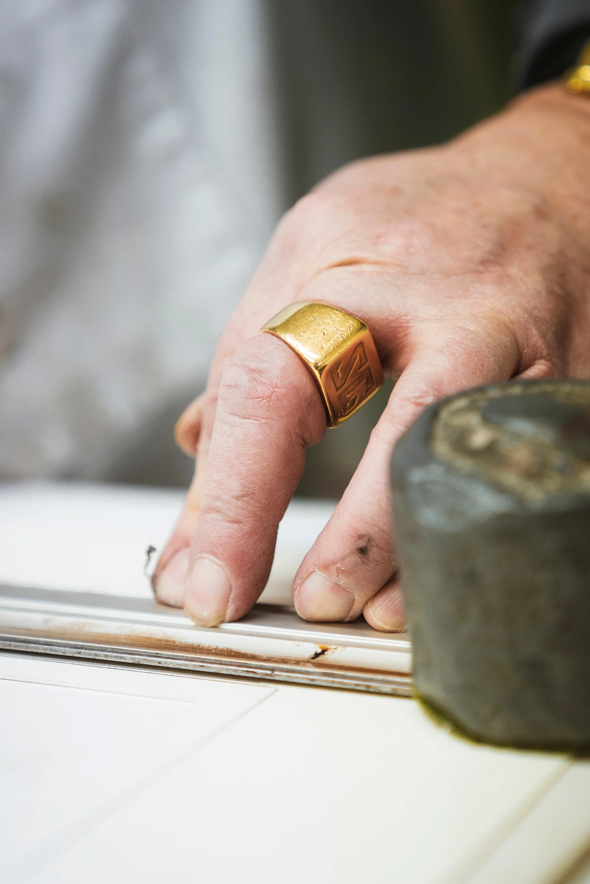 Une main pose une baguette d'encadrement, le maillet à côté