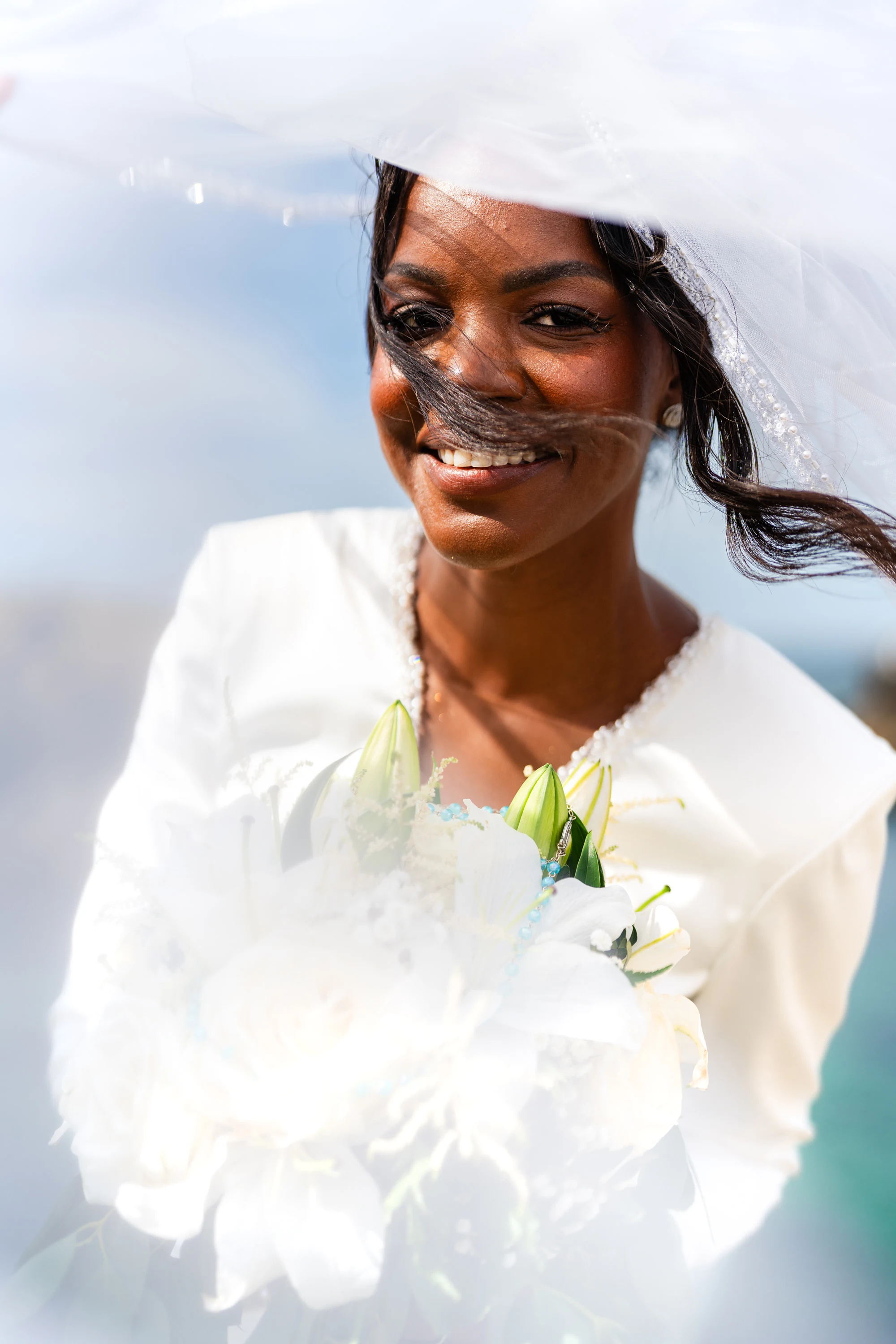 Portrait d'Amandine, le voile emporté par le vent devant son visage, bouquet à la main