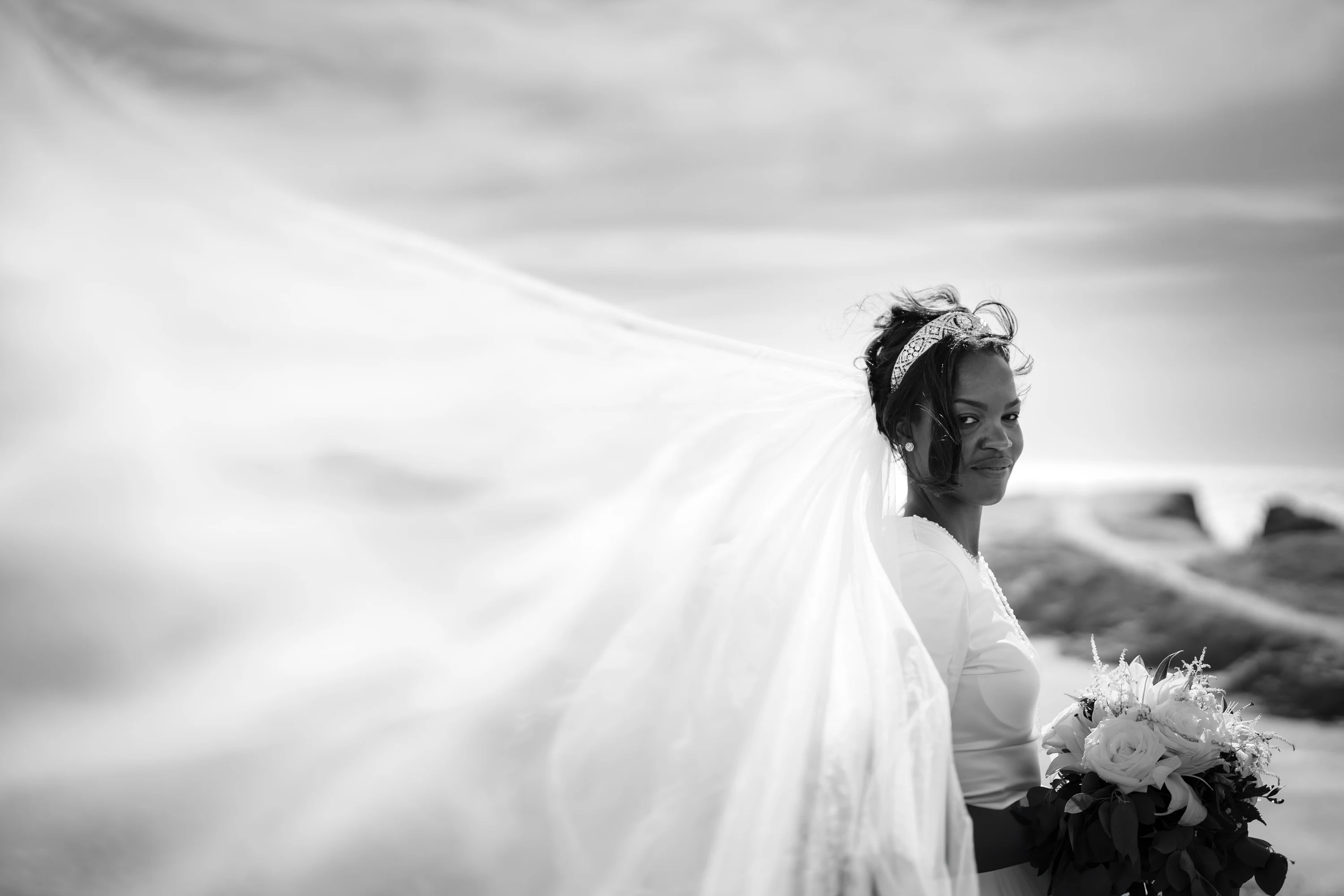 Amandine de profil, le voile étiré par le vent sur toute la largeur de l'image, en noir et blanc