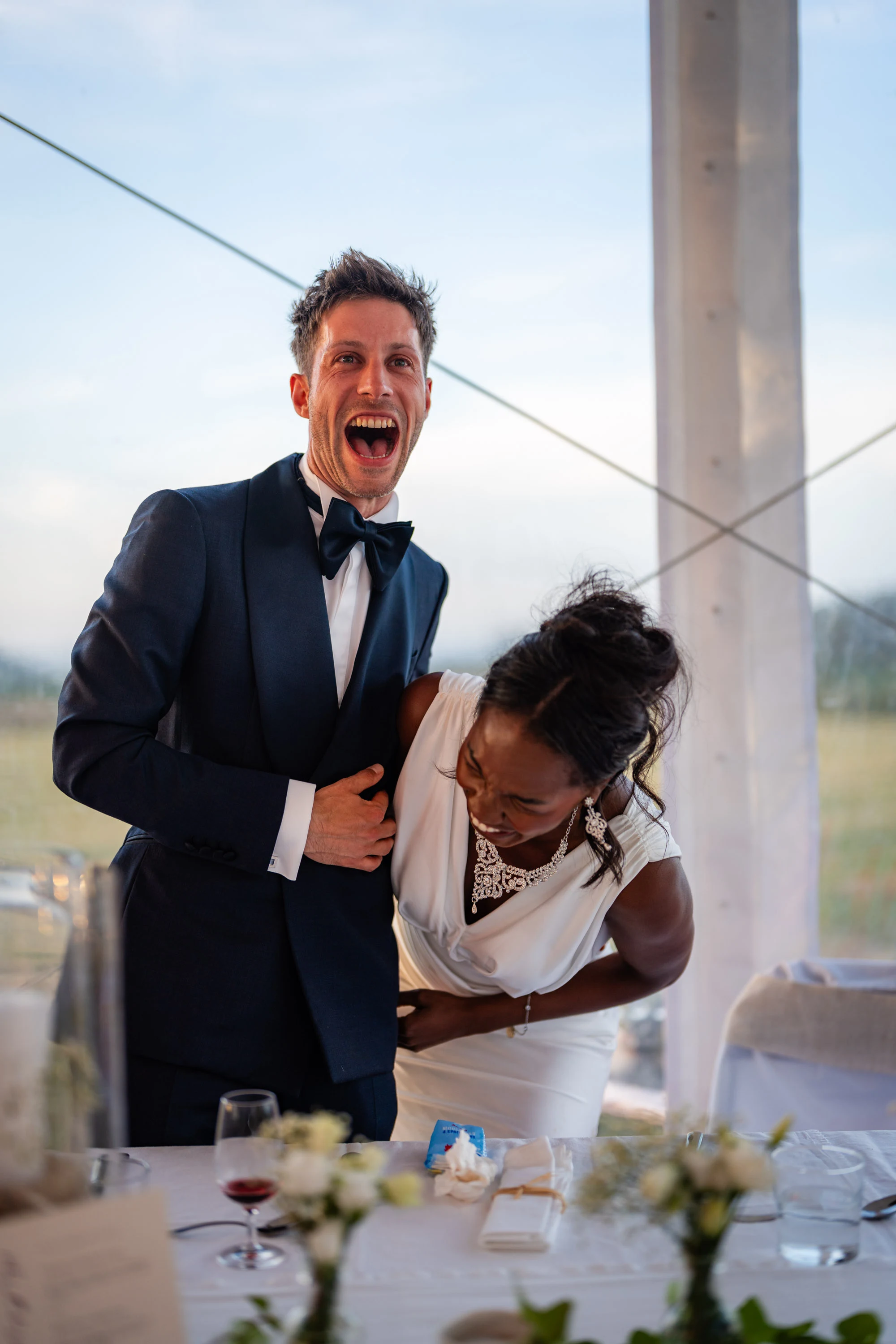 Amandine et Benjamin pliés de rire à leur table, sous le chapiteau