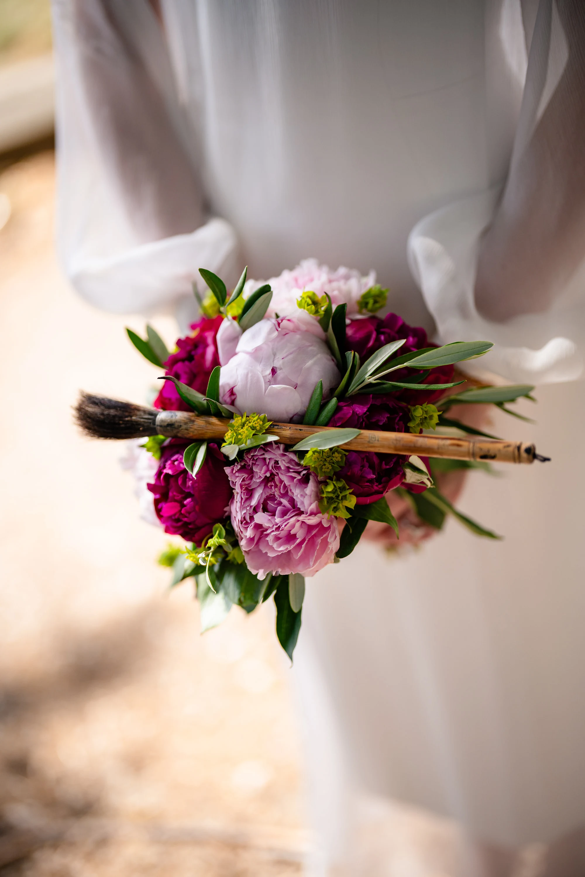 Détail du bouquet de pivoines contre la robe de la mariée